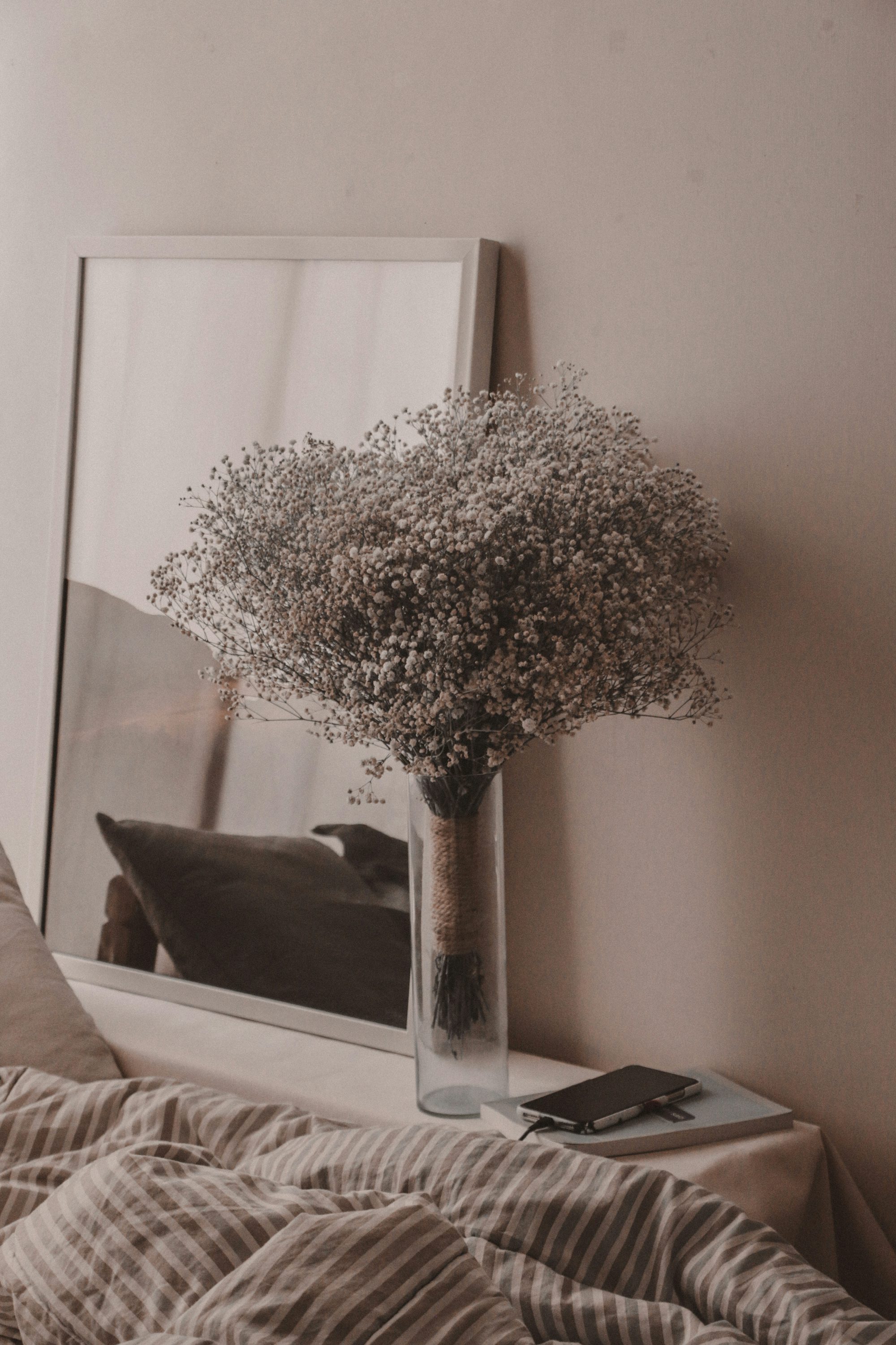 a vase filled with baby's breath sitting on top of a bed