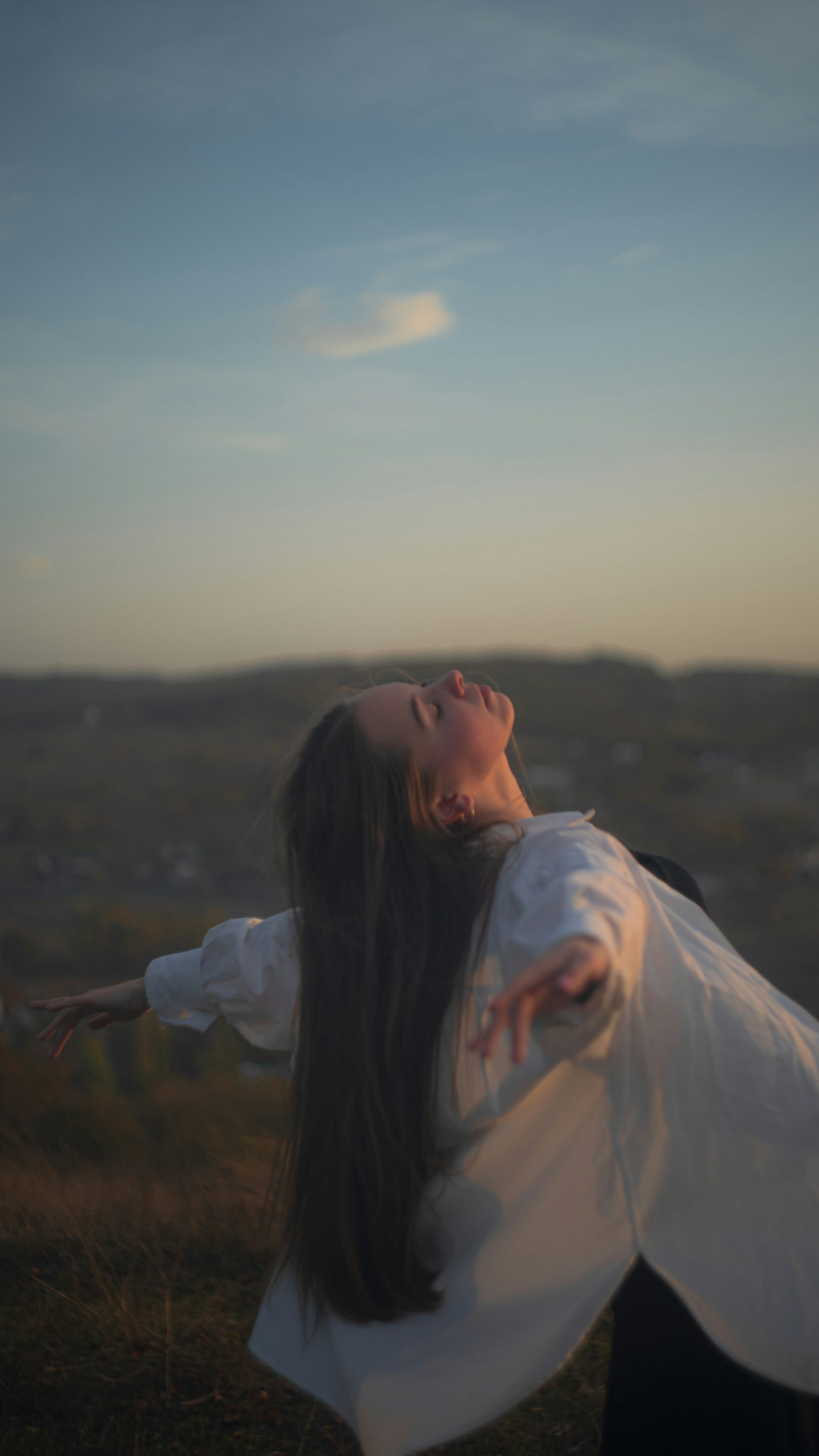 a woman standing in a field with her arms outstretched