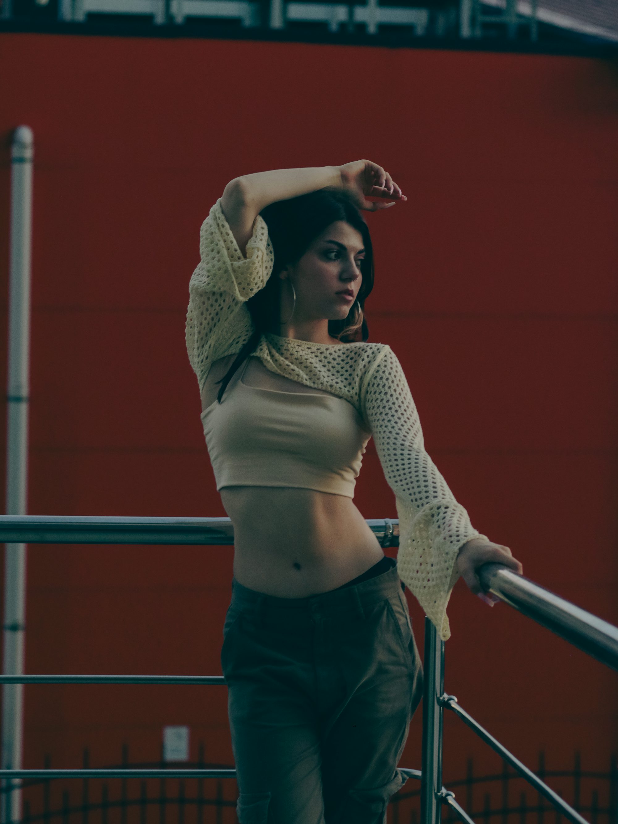 a woman is standing on a railing with her arms behind her head